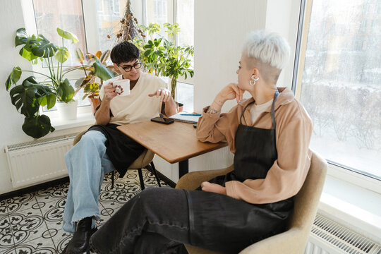 Two young florists drinking coffee in a colorful flower shop