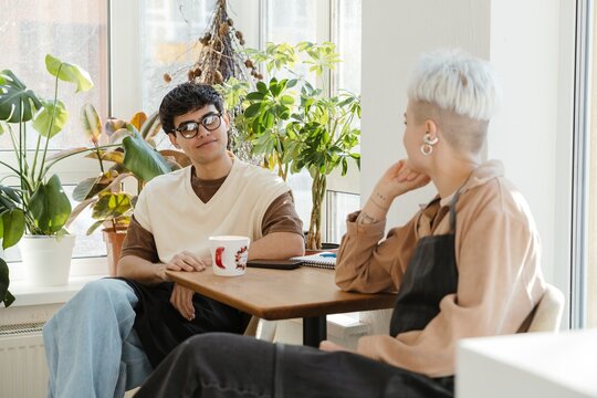 Two young florists drinking coffee in a colorful flower shop