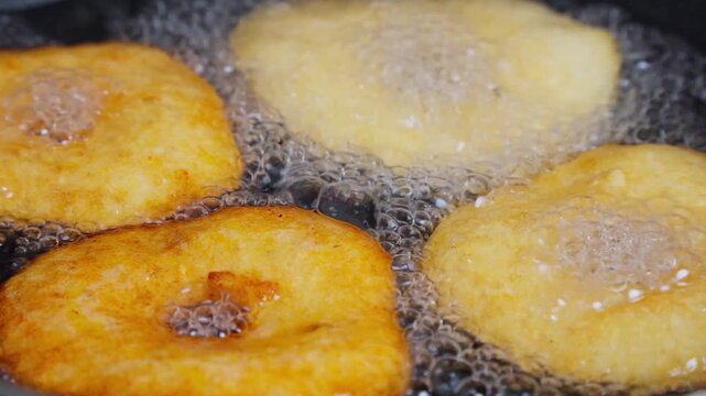 Golden medu vada frying and sizzling in hot oil in a pan