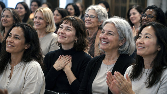 Diverse group of women smiling and applauding during a meeting or seminar showing support, appreciation, community and positive engagement