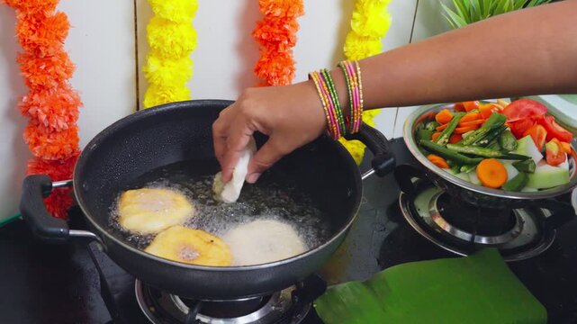 Dropping vada batter into hot oil to fry crispy medu vada during festival