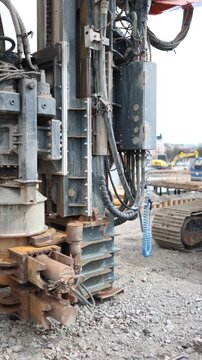 Vertical screen excavator with drilling equipment standing idle at a construction site during a pause in work showing heavy machinery and industrial equipment outdoors