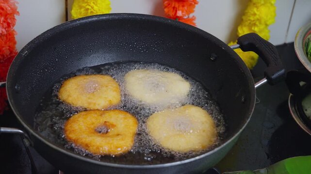 Medu vada frying in a pan of hot oil until golden and crisp