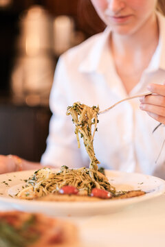 Frau sitzt als Gast im Restaurant und isst eine Speise Pasta