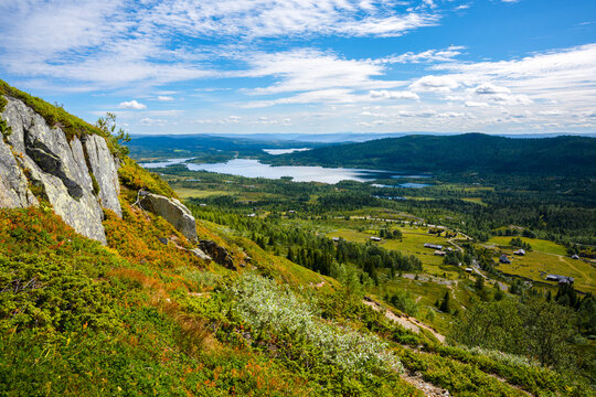 Scenic panoramic view over Hallingdal valley and lake from mountain ridge near Gol, Norway. Scandinavian summer landscape with rocky hills, green fields and blue sky.