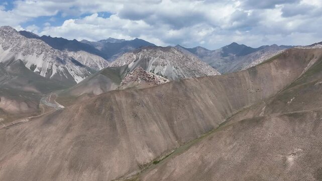 Aerial drone flight approaching Begmat peak, Sary Mogol, in cloudy weather.