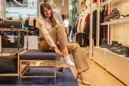 Young pretty woman trying on new shoes in a fashionable boutique