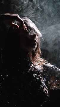 Mysterious woman in sparkling rhinestone veil surrounded by smoke