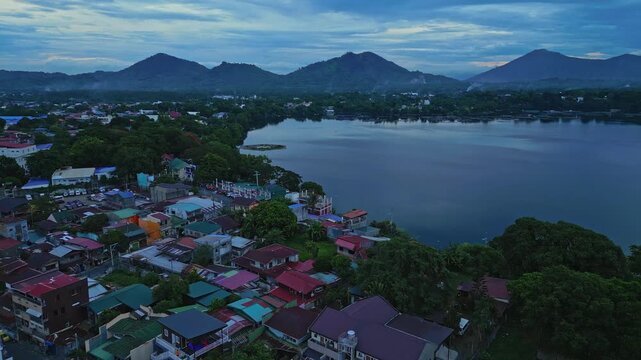 Wide cinematic panorama featuring Iglesia Ni Cristo [San Pablo City, Laguna District Office], residential communities, tropical greenery, and the volcanic mountain landscape of Mount San Cristobal.