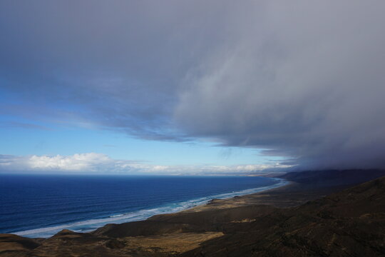 Storm clouds rolling over a coastline seen from above