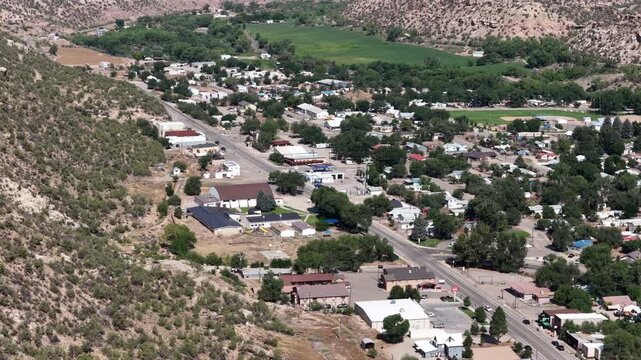 Aerial of small desert townscape and valley floor in Naturita Colorado with residential neighborhoods and desert bluffs