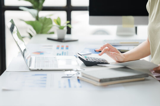 Accounting and Financial Analysis: A person's hands are busy calculating on a calculator, with a laptop and financial reports spread across a desk.