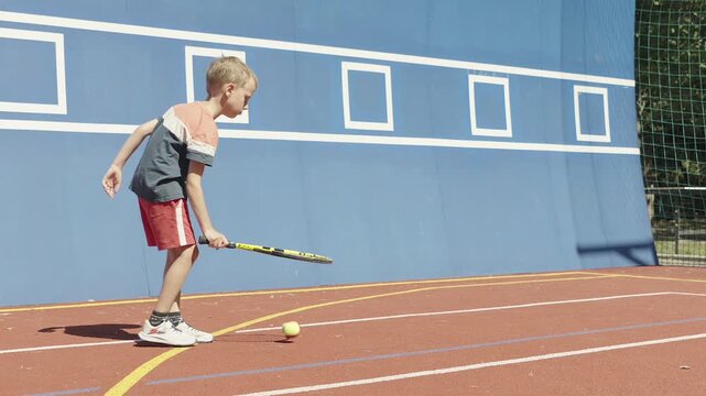 Young boy practicing tennis skills by bouncing a ball on his racket