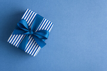 Obraz premium Gift box with blue ribbon on blue background celebration surprise present giving joy special occasion