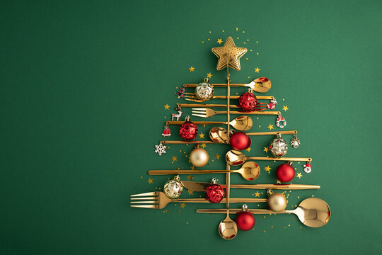 Creative Christmas Tree Made From Golden Cutlery Decorated With Ornaments And Star On Green Background