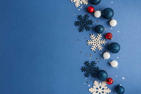 Festive Christmas ornaments and snowflakes arranged on blue background with copy space for holiday greetings
