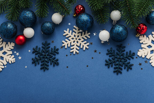 Festive Christmas decorations including snowflakes baubles and pine branches arranged on a blue background
