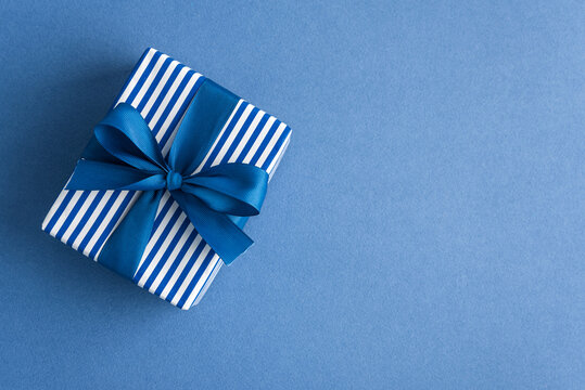 Gift box with blue ribbon on blue background celebration surprise present giving joy special occasion