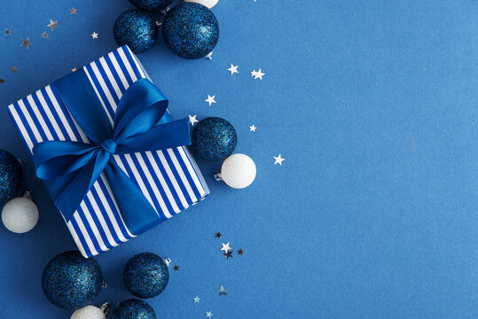 Festive Blue Christmas Gift Box Decorated With Ornaments And Star Confetti On A Blue Backdrop
