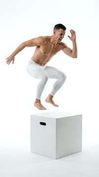 Shirtless athletic male performing box jump exercise on white platform