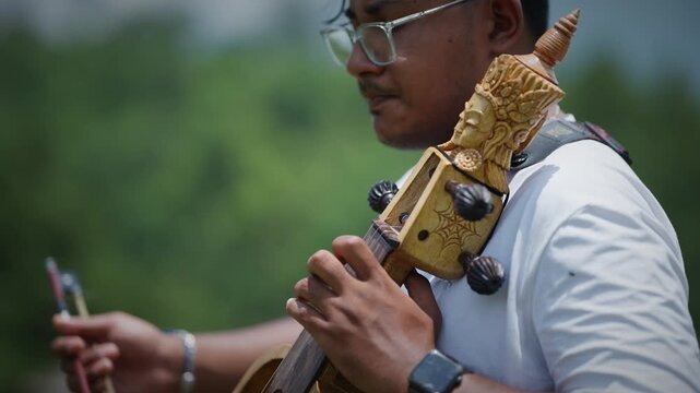 Macro close up of a musician's hand drawing a bow across sarangi strings with intricate carved wood detail glowing in warm sunlight