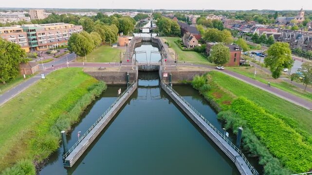 Typical Dutch canal lock with sluice gates and a bridge in town, aerial retreat
