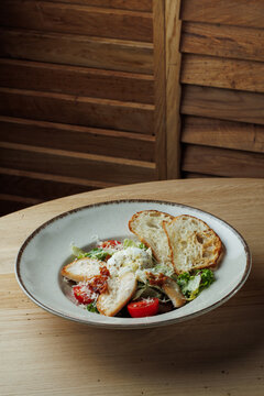 Chicken Caesar salad with poached egg, Parmesan, bacon, tomatoes and rustic bread in vertical composition