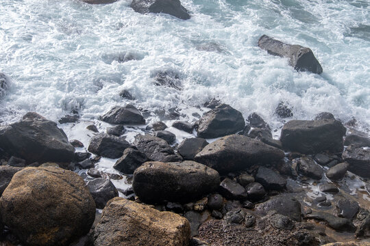 Black Volcanic sand beach and blue water ocean in Madeira, coast Portugal, Atlantic waves sparkle in sun, warm Gulf Stream water flows, peaceful energy, marine life