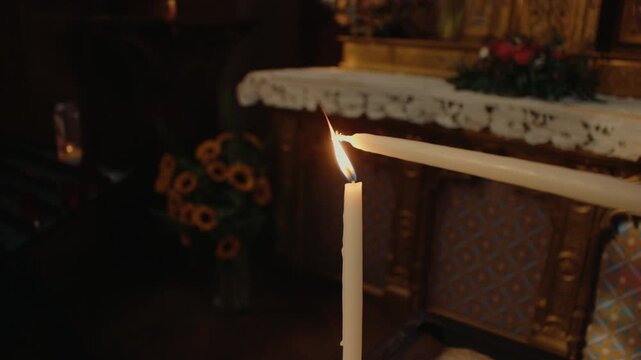 Person lighting a candle inside historic church, creating warm flame for prayer, remembrance and spiritual devotion