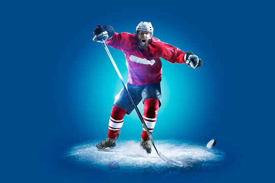 Hockey. Professional hockey player isolated on blue background. Hockey player in action. Hockey concept. Sport