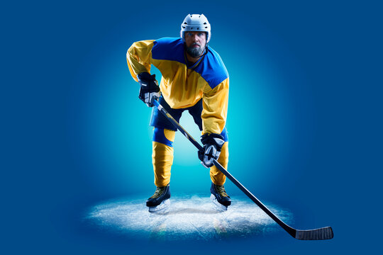 Hockey. Professional hockey player isolated on blue background. Hockey player in action. Hockey concept. Sport