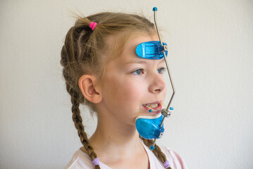 Side profile portrait of young girl wearing orthodontic facemask headgear for class III malocclusion treatment  © Iv