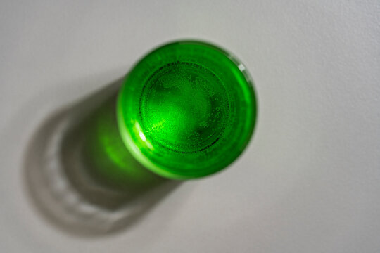 Top view of green carbonated drink in glass, closeup. Flat lay of round transparent glass filled with bright green sparkling soda or alcoholic cocktail casting soft shadow on white background