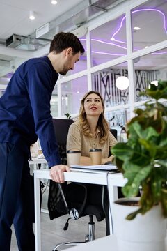 Two coworkers having conversation during a collaborative office meeting