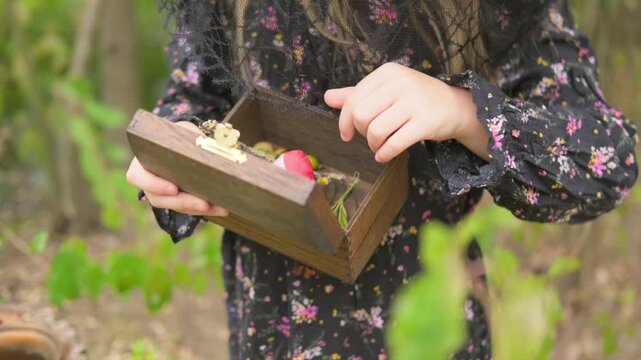 little girl wearing witch hat holding small wooden chest box, secret treasure discovery, fantasy cosplay outdoor portrait, mysterious forest storytelling, child play, Young child discovering magic box