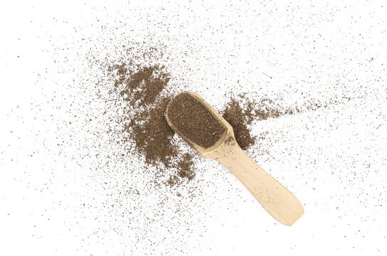 Minced black pepper in wooden spoon, ground peppercorn scattered isolated on white background, top view