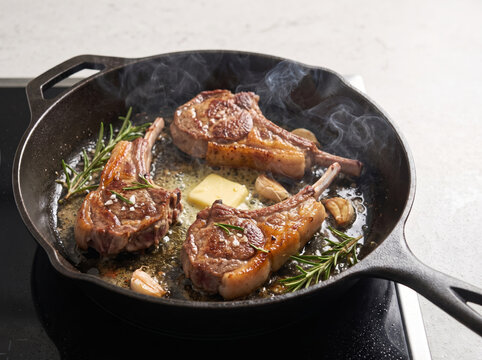 Cooking lamb chops with butter, garlic, and rosemary in a cast iron skillet