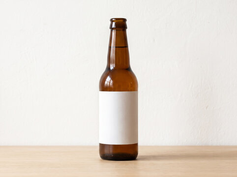 Amber glass beer bottle with a blank white label on a wooden table