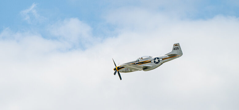 Sola, Norway - June 16 2024: vintage fighter aircraft flying low across cloudy blue sky.