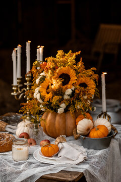 Beautiful fancy fall wedding table decor, countryside style cottage core. Vintage wooden furniture, candlelight, centrepiece with natural sunflowers. Cozy atmosphere, autumn vibes, stylish house decor