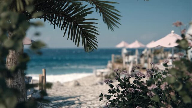 Tropical beach view with palm leaves framing ocean waves and pink umbrellas. Serene seaside resort scene with sandy shore and chairs. Relaxation and vacation concept for summer getaway imagery.