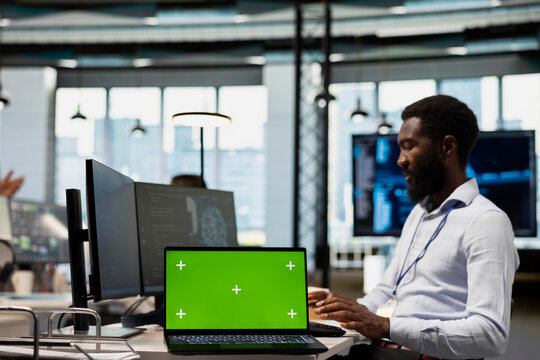 Engineer writes code on an isolated-screen laptop and develops machine learning APIs while troubleshooting software errors in an office.