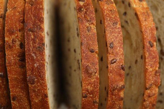 Slices of fresh bread with flax seeds as background, closeup