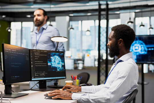 Computer scientist in an office uses AI automation scripts to reduce repetitive coding tasks and apply artificial intelligence technology with a team of programmers within a startup workspace.