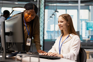 Friendly IT team leader teaches a young software developer to use artificial intelligence, guiding the junior employee through AI tool integration and deep learning APIs during office training.