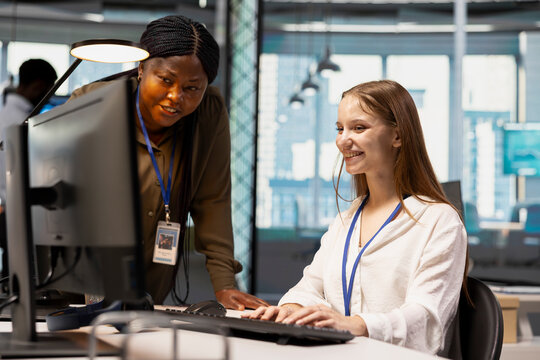 Friendly IT team leader teaches a young software developer to use artificial intelligence, guiding the junior employee through AI tool integration and deep learning APIs during office training.