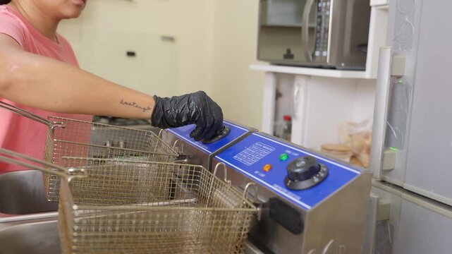 Female chef turning on deep fryer temperature dial