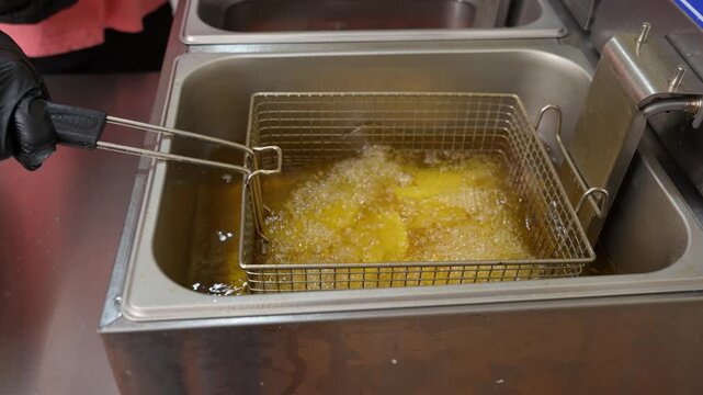 Professional chef frying french fries in deep fryer oil