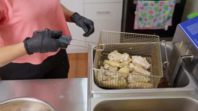 Professional cook deep frying chicken wings in a restaurant kitchen