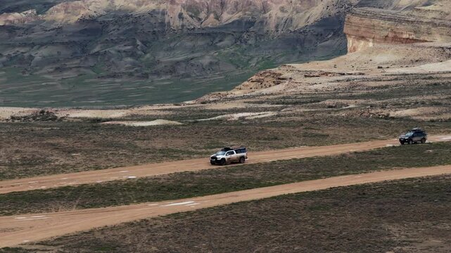 Aerial view of Bozjyra landscape with off-road vehicles driving on dirt tracks through the desert terrain of Aktau, Mangystau Region, Kazakhstan.